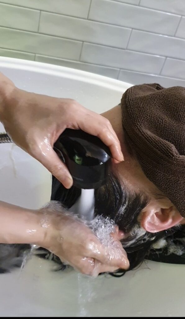 새치 염색 후 염색약의 물빠짐을 방지하기 위해 미지근한 물로 머리를 감고 있는 모습